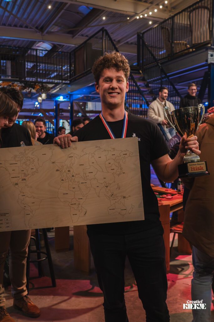 Thijs Blackstone, winnaar van het NK Risk 2025, met de beker en de houten Risk-wereldkaart